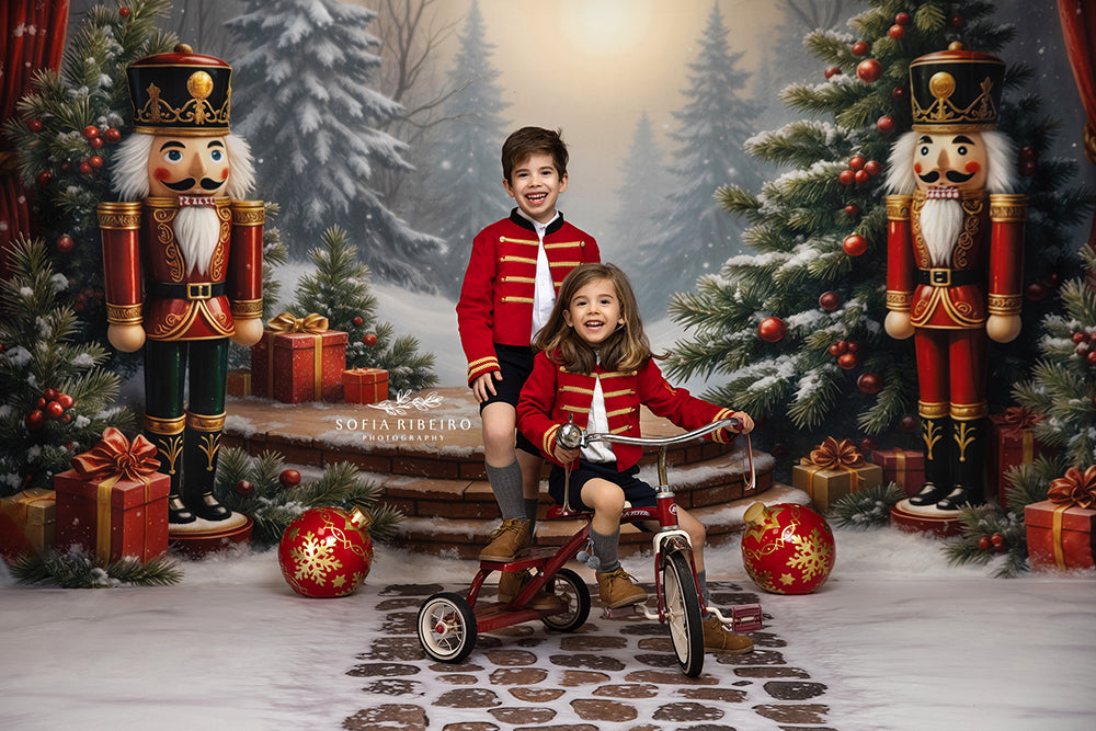 This whimsical Christmas backdrop features two classic nutcrackers standing guard beside snowy trees, red curtains, and festive garlands. A round wooden platform surrounded by wrapped gifts and a glowing winter forest sets the scene for magical holiday portraits.