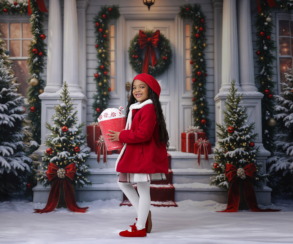 Snowy front porch backdrop with red bows, gift boxes, garlands, and lit wreath—perfect festive setting for cozy Christmas portraits.