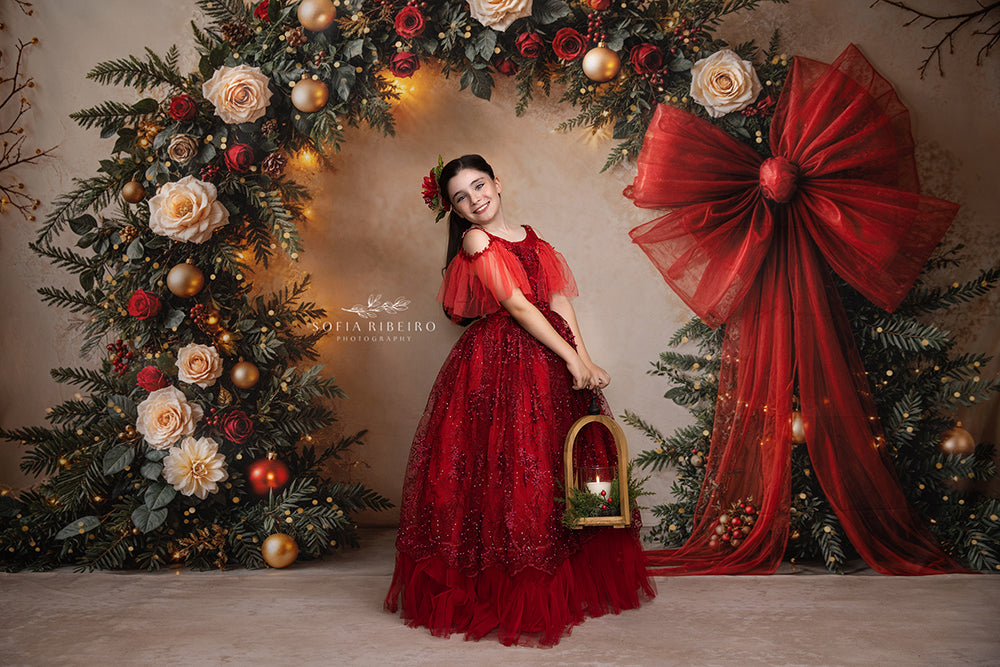 Elegant holiday arch photography background with red and cream florals, gold ornaments, twinkle lights, and a bold red bow—perfect for festive portraits.
