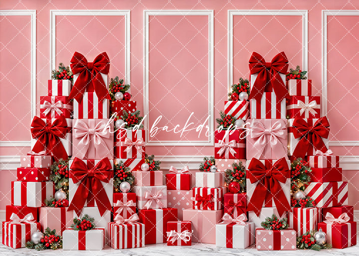 Pink Christmas Gift Wall Photography Backdrop featuring a soft pink wall with white frame accents, stacked red and pink presents, oversized bows, ornaments, berry greenery, and festive holiday shopping-inspired decor.