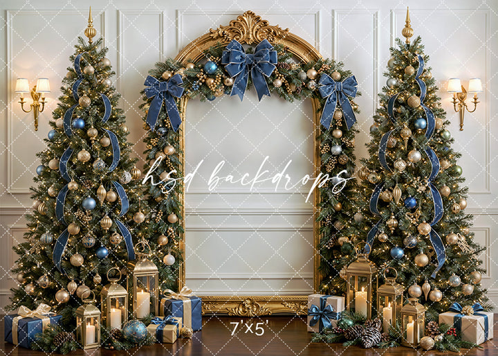 Dusty Blue Christmas Tree photography backdrop with a grand gold arch, decorated Christmas trees, dusty blue velvet bows, lanterns, wrapped gifts, and elegant holiday décor for portrait photography.