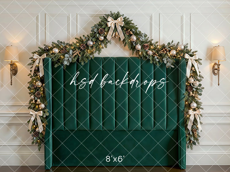 Emerald Holiday Headboard photography backdrop with a green upholstered headboard, festive garland, champagne ornaments, glowing lights, and elegant Christmas bows for portrait photography.