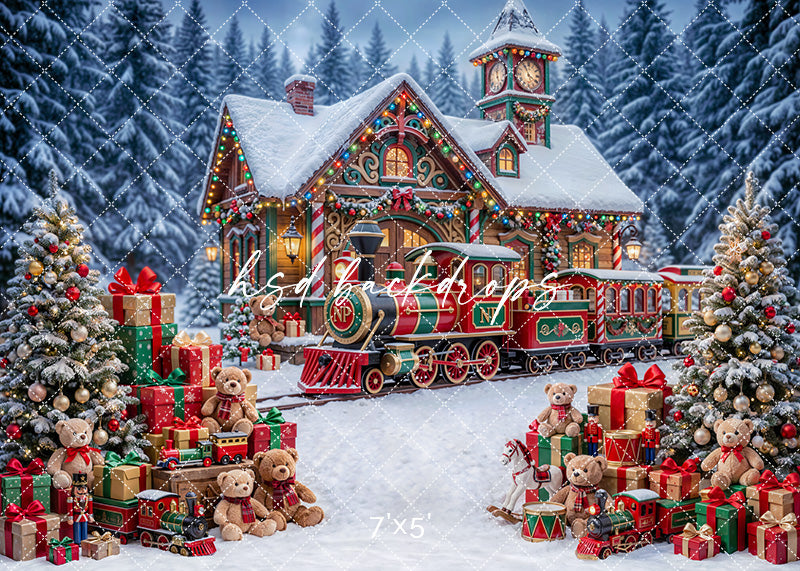 Snowy Toymaker Station photography backdrop with a decorated Christmas train station, snowy trees, toy trains, teddy bears, wrapped gifts, and glowing village lights for holiday portrait photography.