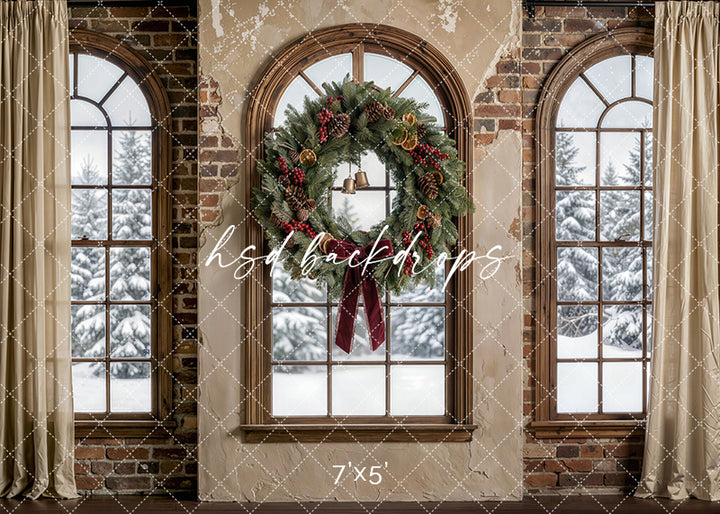 Rustic Noel Window photography backdrop with arched brick windows, snowy evergreen views, soft drapery, and a festive wreath with pinecones, bells, and ribbon for holiday portrait photography.