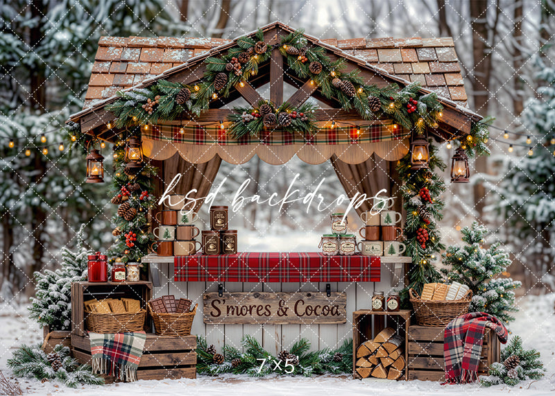 S’mores and Cocoa Stand photography backdrop with a rustic wooden booth, plaid table covering, festive garland, lanterns, evergreen trees, cocoa mugs, and cozy holiday décor for portrait photography.