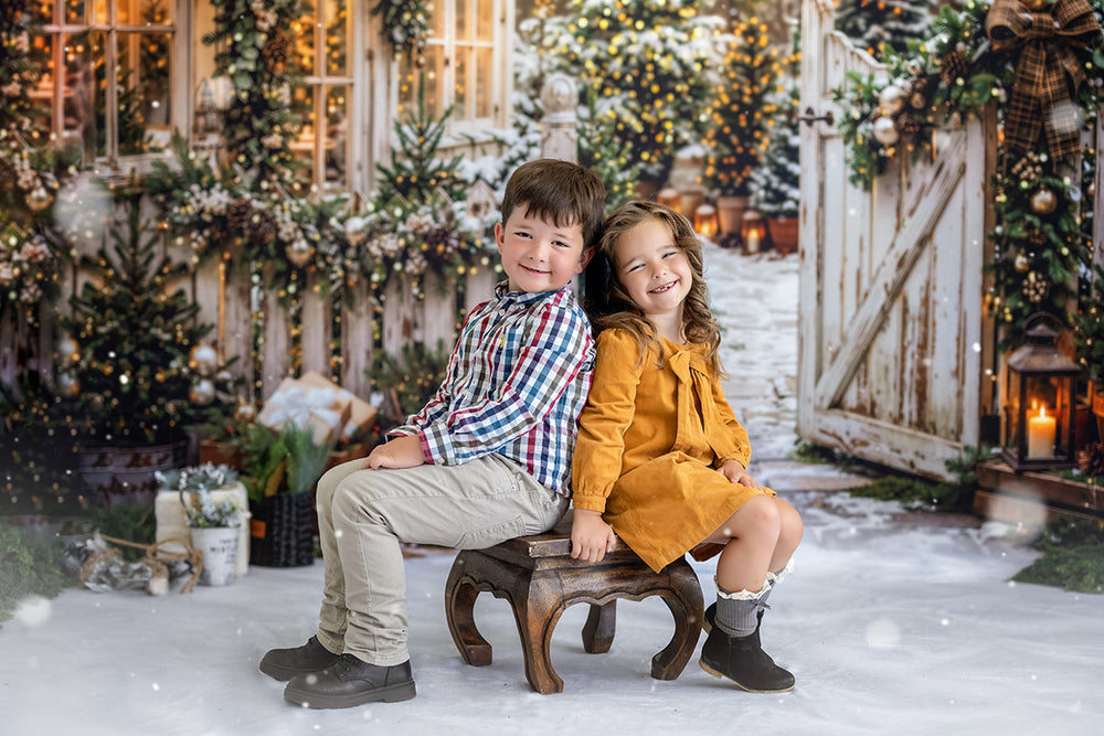 Snowy Christmas greenhouse path photography backdrop with winter trees, glowing holiday lights, white garden gate, evergreen garland, lanterns, and cozy holiday portrait styling.