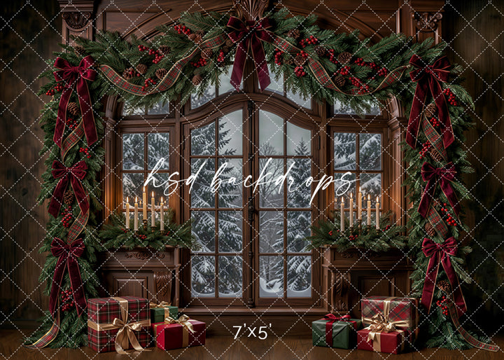 Winter Garland Window Christmas photography backdrop with arched snowy window, rich wood paneling, evergreen garland, burgundy bows, plaid ribbon, candlelight, and wrapped holiday gifts.