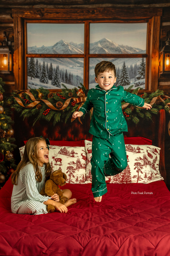 Christmas cabin bedroom portrait backdrop with burgundy bed, snowy mountain scenery, evergreen garland, pinecones, lanterns, wrapped gifts, and cozy winter holiday décor.
