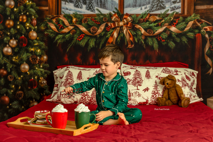 Rustic winter lodge Christmas backdrop with mountain window scene, cabin wood walls, burgundy bed, evergreen garland, holiday pillows, Christmas tree, and cozy winter portrait details.