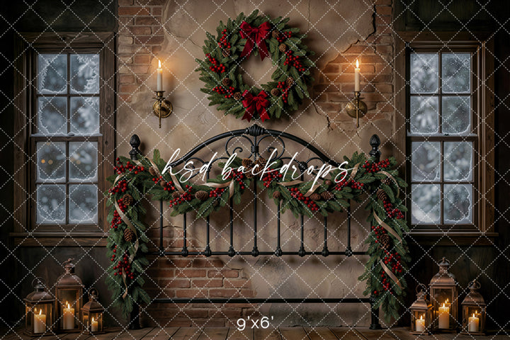 Evergreen Bedframe Christmas photography backdrop with black iron bedframe, rustic brick wall, snowy windows, candle sconces, lanterns, evergreen garland, red berries, pinecones, and festive wreath.