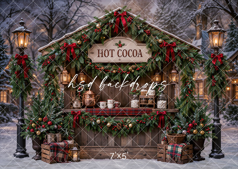 Christmas Hot Cocoa Stand photography backdrop with rustic cocoa booth, evergreen garland, red bows, glowing lanterns, plaid accents, snowy trees, mugs, treat jars, and cozy holiday market styling.
