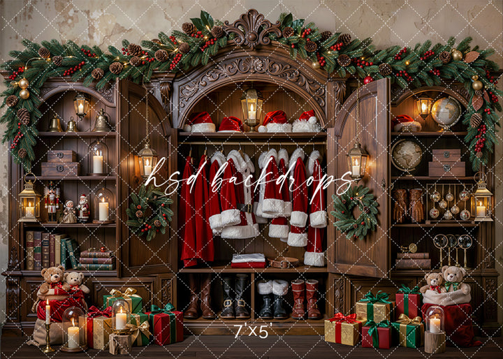 Santa’s Heirloom Wardrobe Christmas photography backdrop with ornate wooden wardrobe, Santa suits, boots, hats, lanterns, bookshelves, teddy bears, wrapped gifts, evergreen garland, and classic holiday styling.