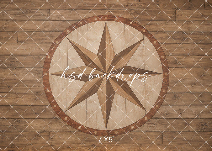 Compass Star Wood Floor photography backdrop with warm wood plank texture, large compass star medallion, circular inlaid border, rustic brown tones, and classic studio floor styling.