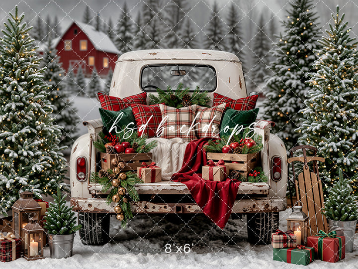 Vintage Christmas Truck Bed photography backdrop with rustic white pickup truck, snowy tree farm, evergreen Christmas trees, plaid pillows, wrapped gifts, lanterns, sled, and cozy winter holiday styling.