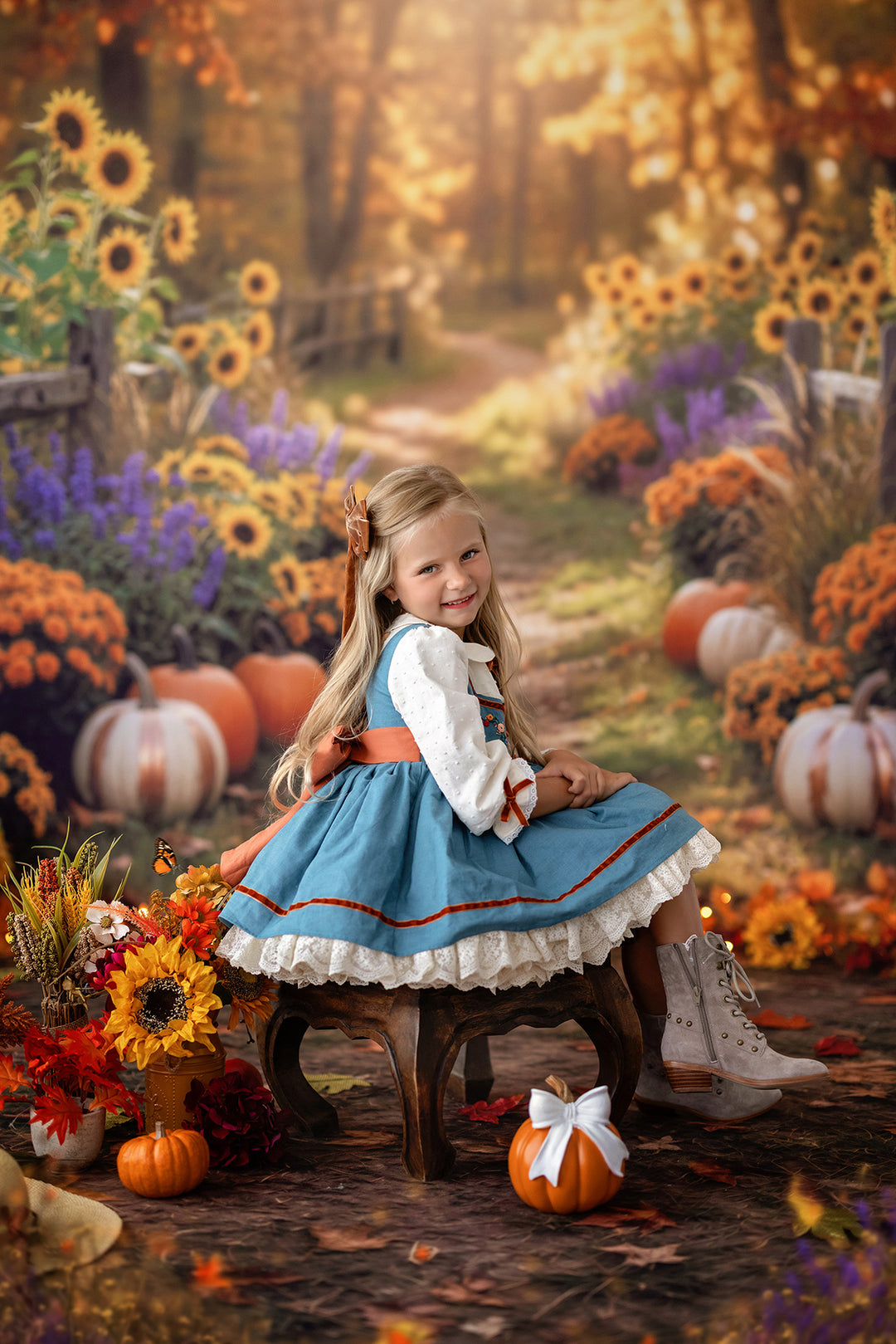 Cozy fall sunflower trail backdrop with pumpkins, orange mums, purple flowers, wooden fencing, glowing autumn light, and warm seasonal portrait details.