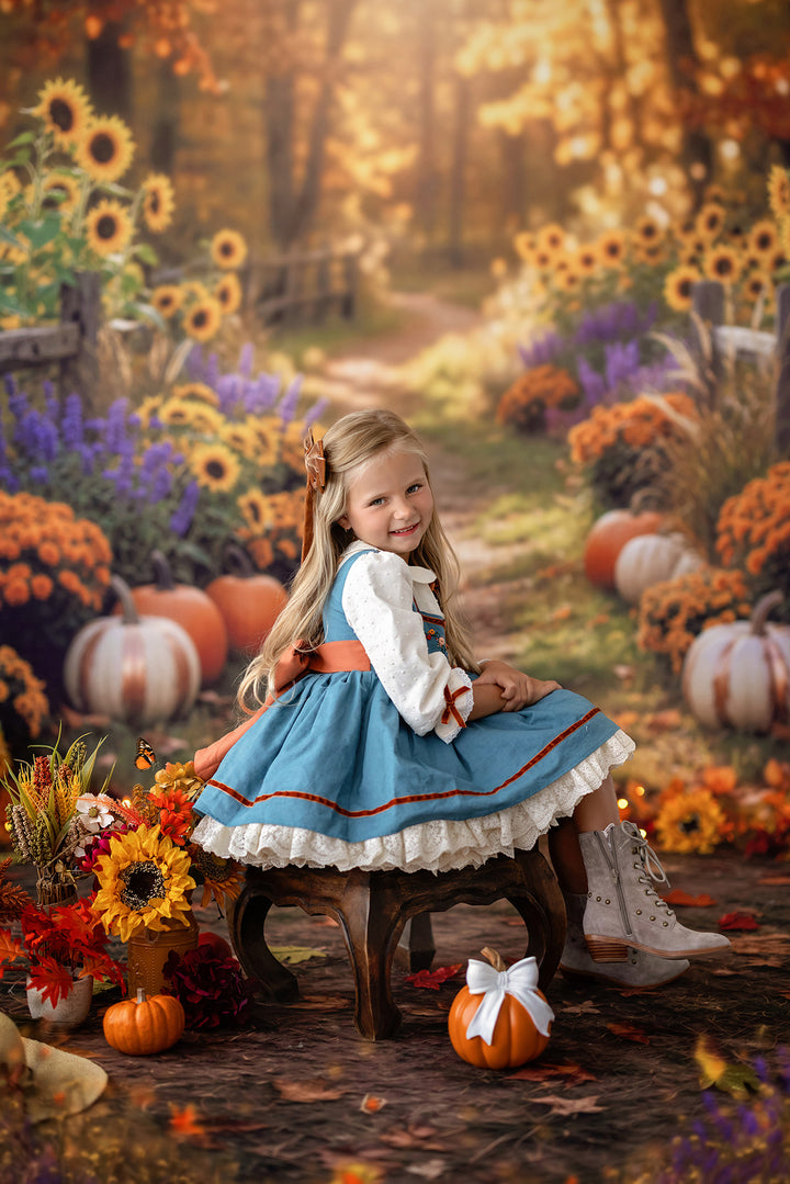 Cozy fall sunflower trail backdrop with pumpkins, orange mums, purple flowers, wooden fencing, glowing autumn light, and warm seasonal portrait details.