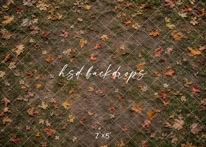 Fallen Leaves Orchard floor mat with earthy ground texture, scattered autumn leaves, mossy grass details, warm brown tones, and rustic fall studio floor styling.