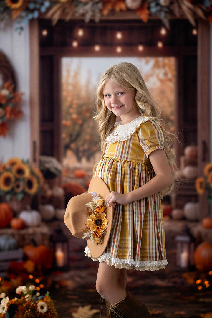 Rustic autumn barn photography backdrop with seasonal pumpkins, hay bales, sunflowers, fall foliage, and a young girl in a vintage-inspired harvest outfit.