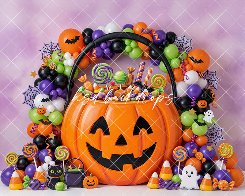 Jack-O’-Lantern Candy Bucket Photography Backdrop featuring a smiling pumpkin candy bucket, colorful Halloween balloon garland, candy corn, lollipops, bats, ghosts, spider webs, and playful trick-or-treat sweets.