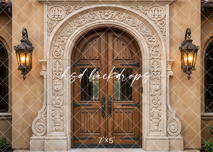 Ornate Spanish Revival archway backdrop with carved stone details, wooden double doors, warm stucco walls, and vintage lantern sconces.