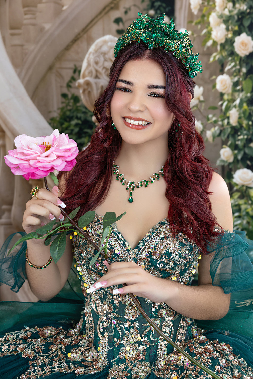 Royal palace staircase quinceañera photography backdrop with sweeping stone staircases, ornate balustrades, cascading white roses, and a young woman in an emerald green quinceañera dress.