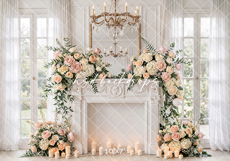 Blush rose fireplace photography backdrop with white fireplace, chandelier, sheer curtains, glowing candles, and soft floral arrangements for elegant maternity and motherhood portraits.