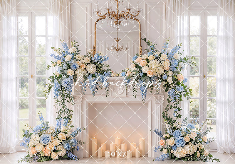Blue rose fireplace photography backdrop with white fireplace, chandelier, sheer curtains, glowing candles, and ivory and blue floral arrangements for elegant maternity portraits.