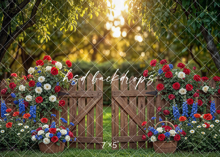 Rustic patriotic garden gate photography backdrop with wooden gate, red white and blue flowers, and sunlit outdoor setting for Fourth of July portraits.
