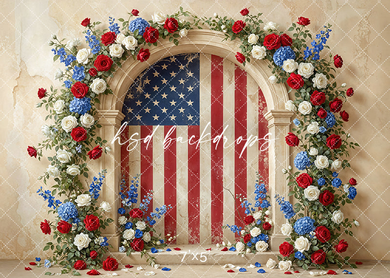 Patriotic floral arch photography backdrop with red white and blue flowers and American flag background for Fourth of July portraits.