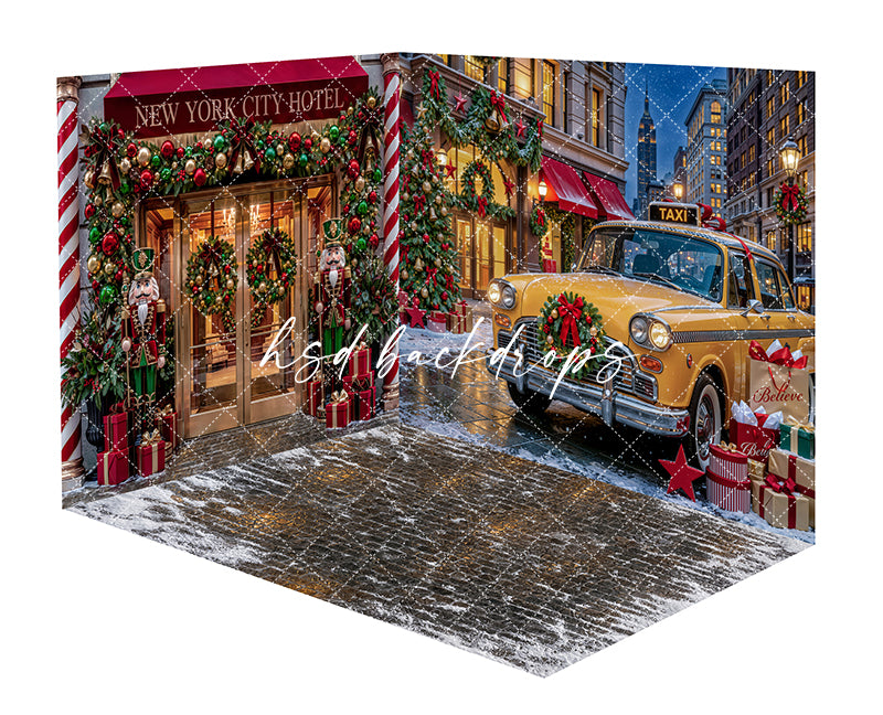 Christmas Taxi Storefront Room Photography Backdrop featuring a festive New York holiday hotel entrance with a yellow taxi, snowy street, garland, wreaths, nutcrackers, wrapped gifts, and glowing Christmas lights.