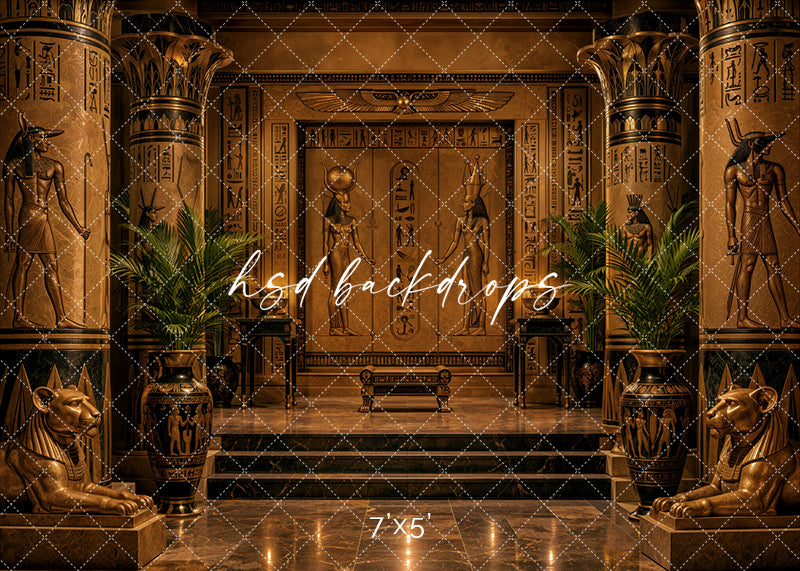 Golden Egyptian Temple photography backdrop with ornate gold columns, hieroglyphic wall details, Egyptian-inspired statues, sphinx accents, palm greenery, marble steps, reflective floor, and dramatic luxury studio lighting.