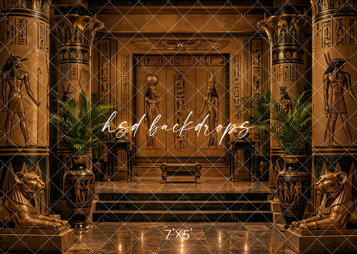 Golden Egyptian Temple photography backdrop with ornate gold columns, hieroglyphic wall details, Egyptian-inspired statues, sphinx accents, palm greenery, marble steps, reflective floor, and dramatic luxury studio lighting.