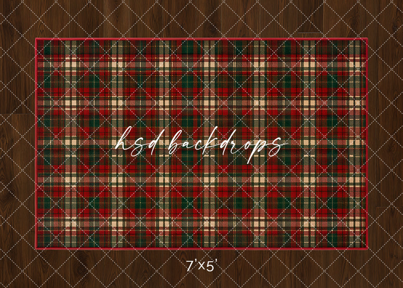 Tartan Christmas rug photography backdrop with classic red, green, cream, and black plaid pattern on a warm wood floor for cozy holiday studio portraits.