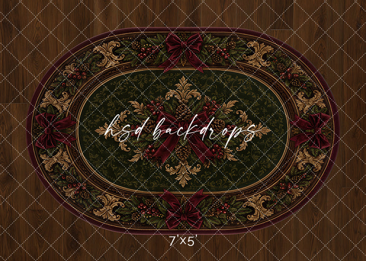 Heirloom Christmas rug photography backdrop with deep green oval rug design, burgundy ribbon accents, ornate gold details, pine greenery, berries, and warm wood floor styling for holiday portraits.