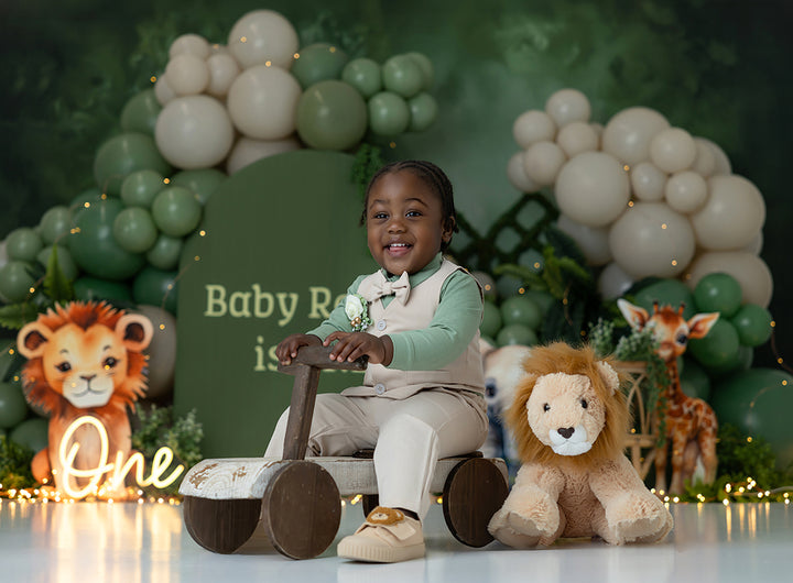 Savannah Vibes safari cake smash photography backdrop with sage green arches, neutral balloon clusters, greenery, lion, elephant, and giraffe for boys birthday portraits.