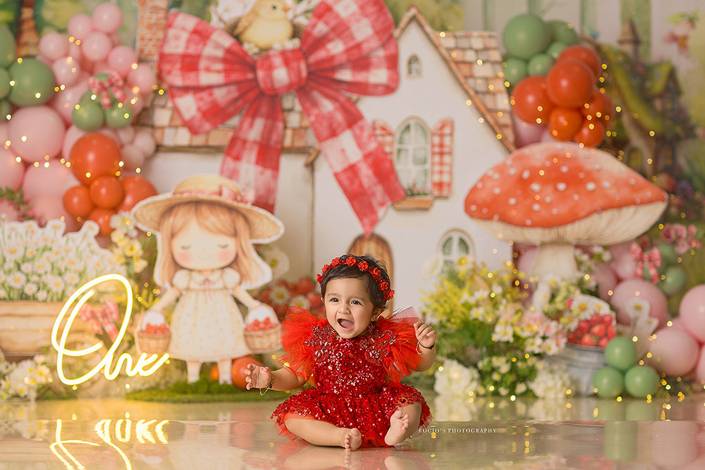 Sweet Strawberry Cottage cake smash photography backdrop with a whimsical cottage, oversized red gingham bows, strawberries, daisies, balloons, and floral details for girls birthday portraits.