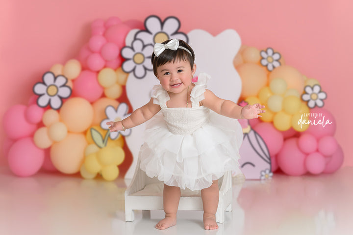Lil Miss Daisy cake smash photography backdrop with pink and yellow balloon clusters, daisy accents, and sweet birthday details for girls portraits.