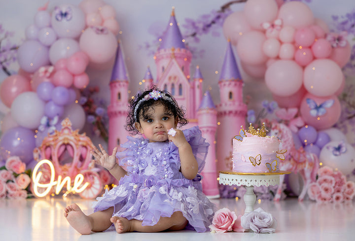 Once Upon a Time Castle photography backdrop with a pink fairytale castle, pastel balloons, butterflies, florals, princess carriage, and whimsical birthday details for girls portrait photography.