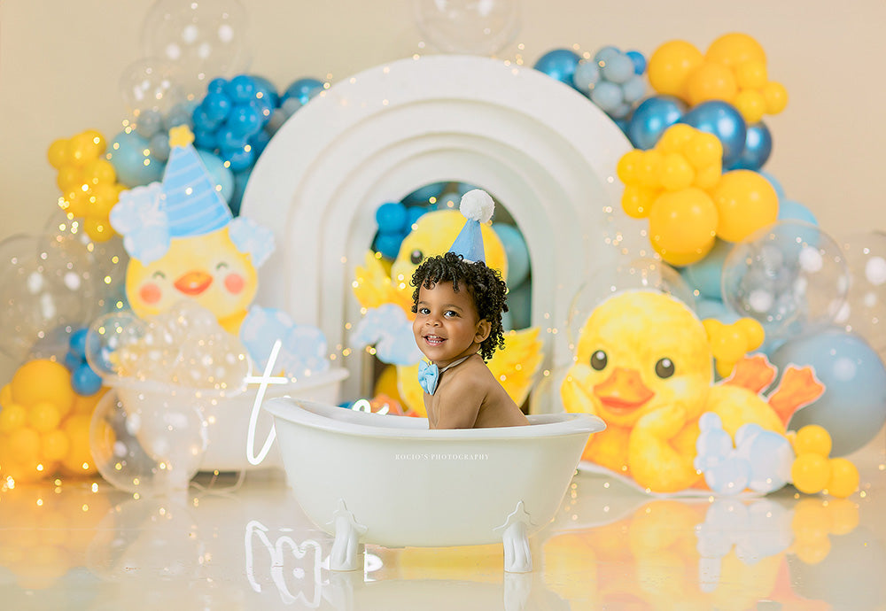 Rubber Ducky Birthday photography backdrop with yellow duck accents, blue and yellow balloons, bubbles, layered arches, and playful bath time styling for boys birthday portraits.