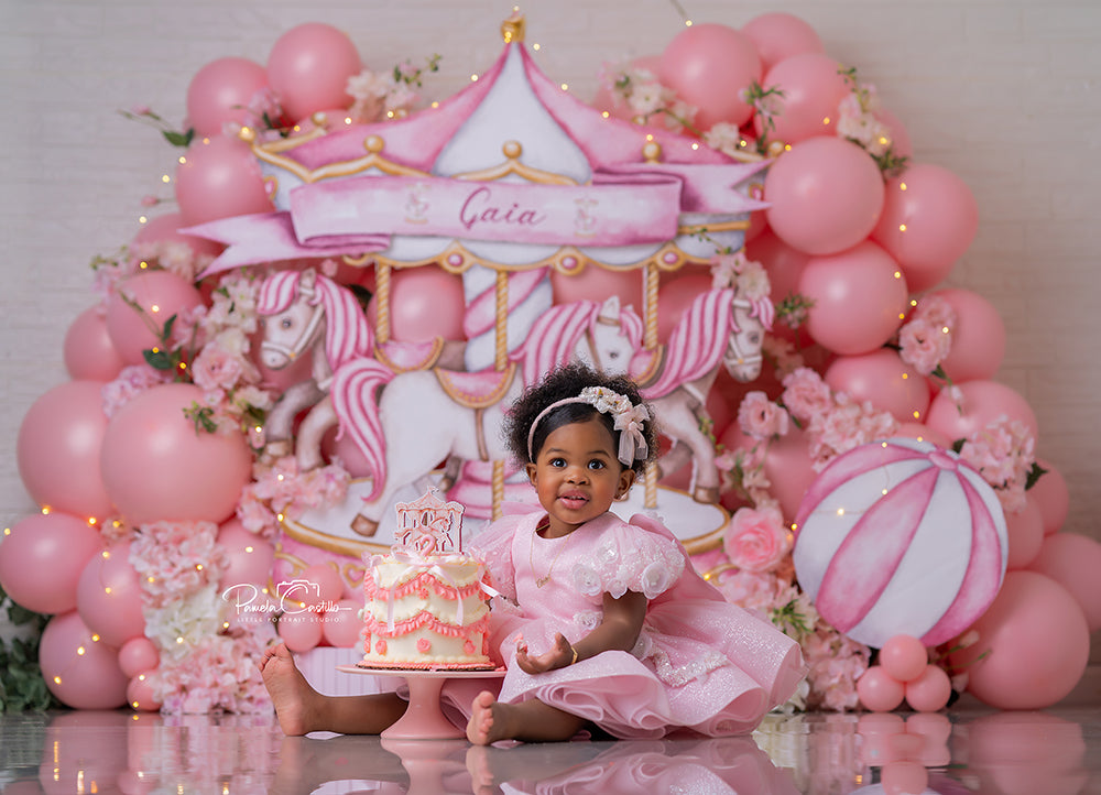 Pink Carousel Birthday photography backdrop with a pastel pink carousel, carousel horses, soft pink balloons, and floral accents for girls birthday portrait photography.