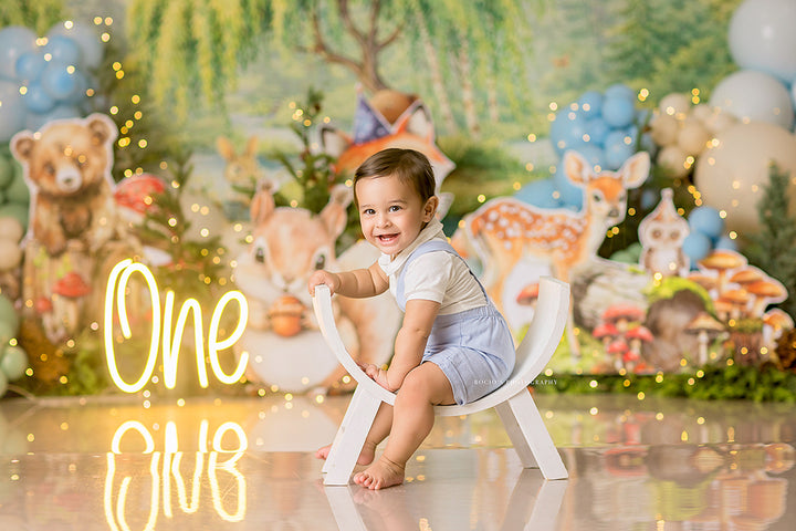 Woodland Animal Party photography backdrop with forest animals, soft blue and green balloons, mushrooms, greenery, and whimsical woodland birthday styling for portrait photography.