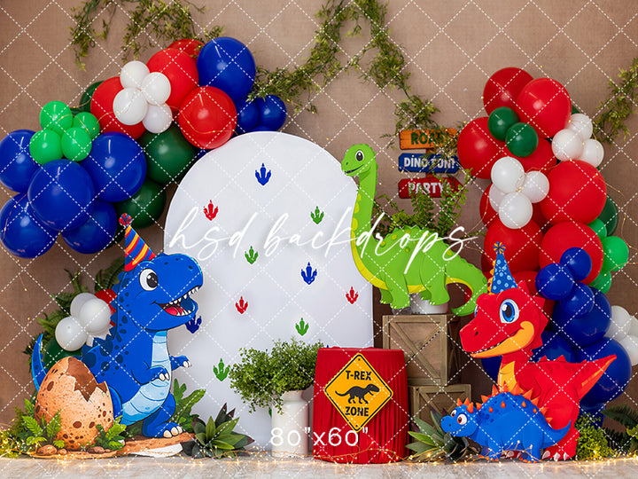 T-Rex birthday party photography backdrop with colorful balloon garlands, playful dinosaur characters, tropical greenery, party hats, dinosaur footprints, and cake smash props.