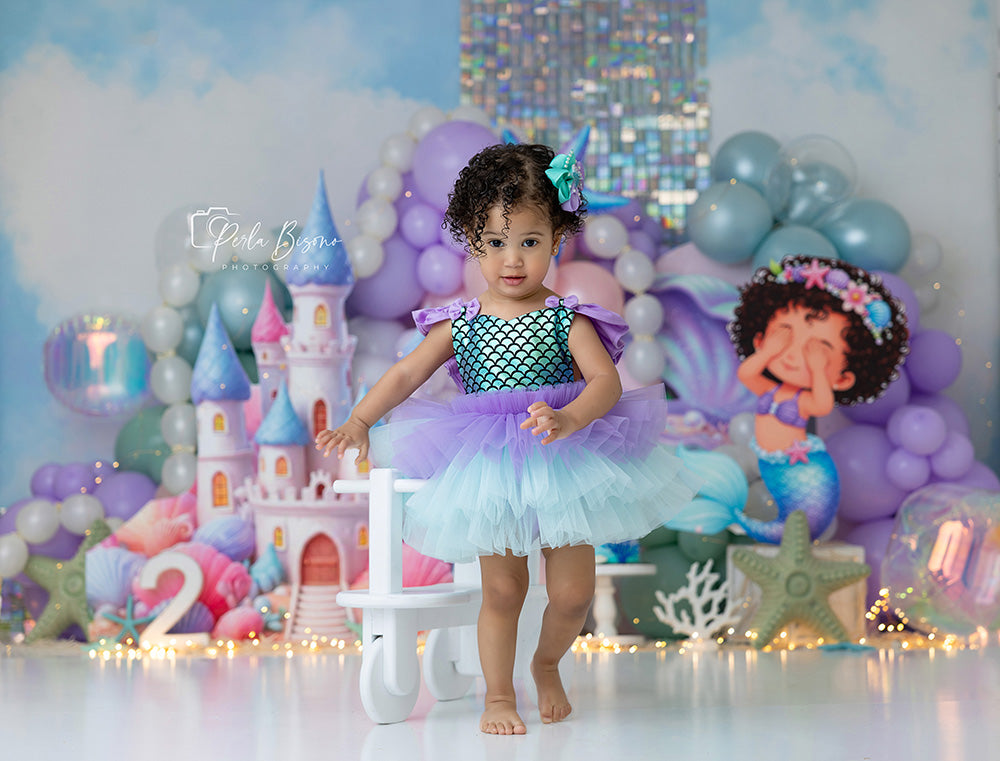 Sea of Dreams Mermaid Castle photography backdrop with pastel balloons, mermaid castle, seashells, starfish, iridescent accents, and whimsical under the sea birthday styling.