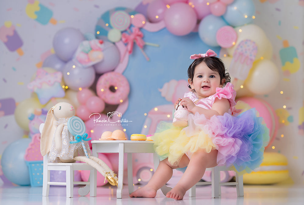 Sweet Treats Ice Cream Truck photography backdrop with pastel balloon garlands, pink ice cream truck, lollipops, donuts, popsicles, macarons, candy details, and playful cake smash birthday styling.