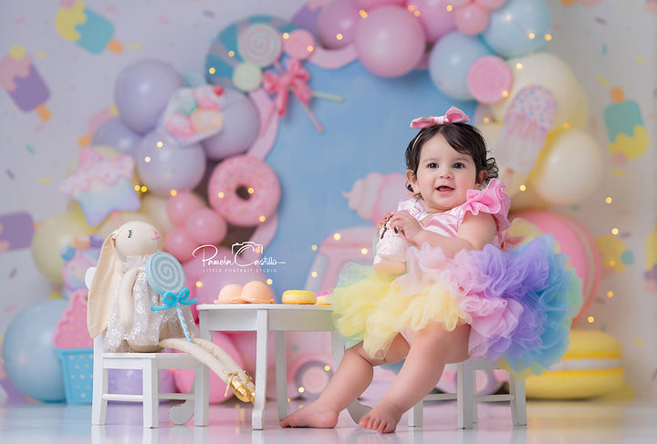 Sweet Treats Ice Cream Truck photography backdrop with pastel balloon garlands, pink ice cream truck, lollipops, donuts, popsicles, macarons, candy details, and playful cake smash birthday styling.