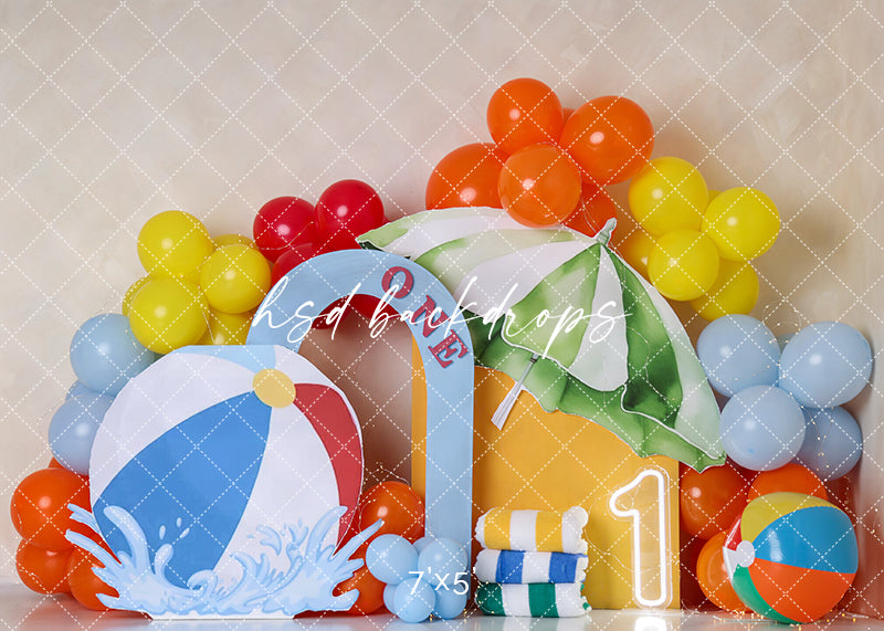 Splish Splash Birthday photography backdrop with colorful beach balls, bright balloons, striped beach umbrella, stacked towels, splash accents, and first birthday styling.