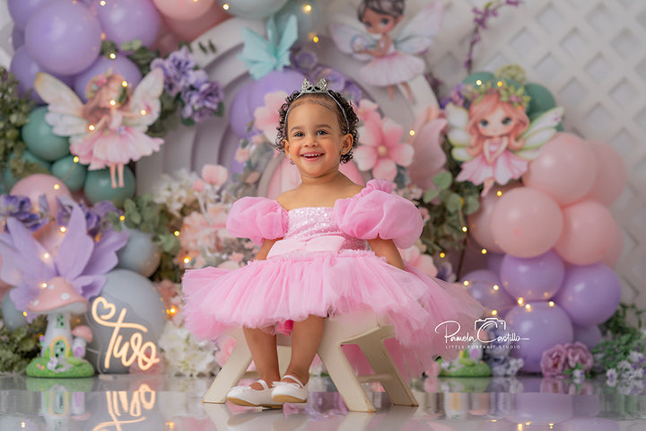 Enchanted Fairy Garden Gate backdrop with pastel balloons, flowers, and whimsical fairies around a pink door.