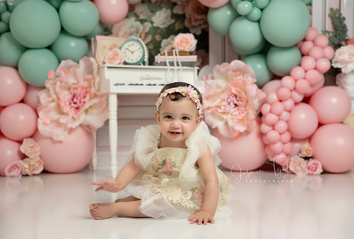 Peony Piano Balloon Arch backdrop with pink and green balloons, vintage piano, and oversized peonies.