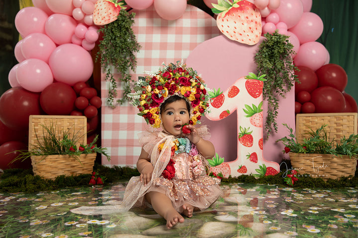 Strawberry Patch Party backdrop with pink balloons, gingham, strawberries, and picnic props.