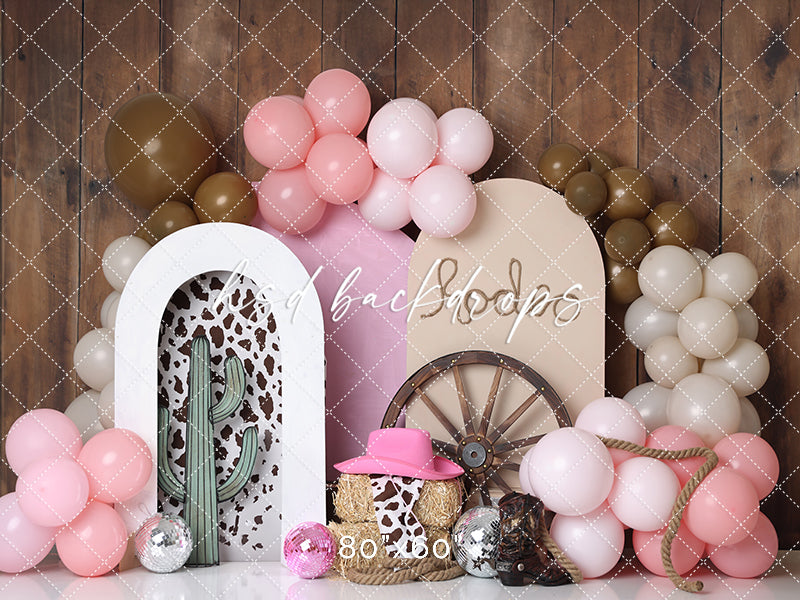 Cowboy-themed first birthday backdrop with cow print, balloons, and "One" sign